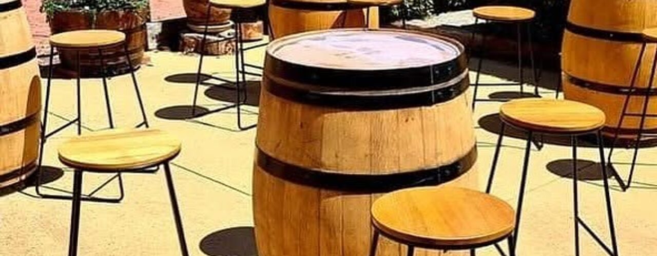 Wine barrel bar tables and stools set up for an outdoor party